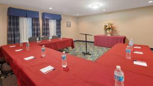 a meeting room with two red tables and chairs with water bottles at SureStay Plus Hotel by Best Western Roanoke Rapids I-95 in Roanoke Rapids +29 photos