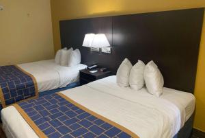 a hotel room with two beds and a lamp at Days Inn & Suites by Wyndham Tampa/Raymond James Stadium in Tampa