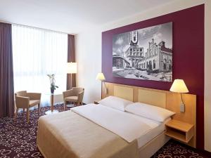a hotel room with a bed and a large painting on the wall at Mercure Hotel Dortmund City in Dortmund