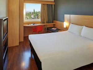 a hotel room with a bed and a desk and a window at ibis Sorocaba in Sorocaba