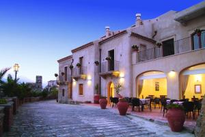 una strada di ciottoli con tavoli e sedie di fronte a un edificio di Resort Borgo San Rocco a Savoca