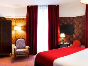 a hotel room with a red bed and a chair at Hotel Carlton Lyon - MGallery Hotel Collection in Lyon