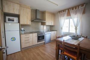 cocina con nevera blanca y mesa de madera en Apartamentos Sarela, en Santiago de Compostela