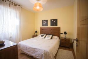 1 dormitorio con 1 cama con sábanas y almohadas blancas en Apartamentos Sarela, en Santiago de Compostela
