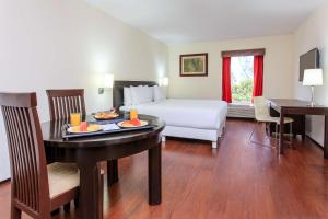 una camera d'albergo con un letto e un tavolo con cibo sopra di NH Coatzacoalcos a Coatzacoalcos