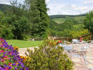 a patio with a table and chairs and flowers at Llanerchindda Farm Guest House in Cynghordy