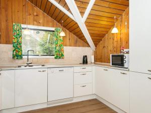 Arrildにある6 person holiday home in Toftlundの白いキャビネットと木製の天井が備わるキッチン