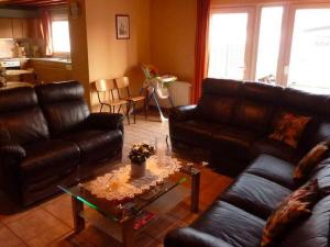 a living room with leather couches and a coffee table at Cozy Cottage in Baugnez Malmedy with Sauna in Malmedy