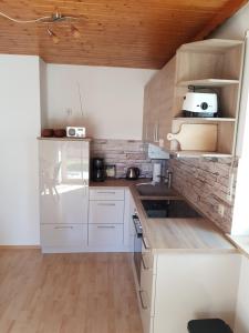 una cocina con electrodomésticos blancos y techos de madera. en Ferienwohnung Am Kirchberg, en Achslach