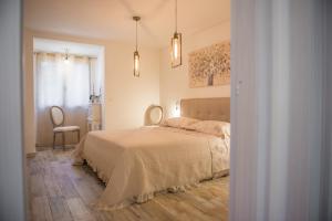 a white bedroom with a bed and a chair at Sa tanca 'e Pedduzza in Orosei