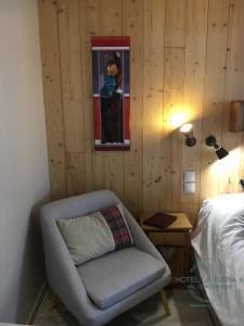 een slaapkamer met een stoel en een foto aan de muur bij Hotel la Turra in Termignon