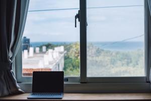 um computador portátil sentado numa mesa em frente a uma janela em Go On Vacation Hostel Green Island em Green Island
