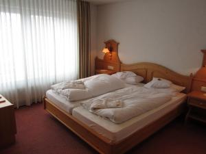 a bedroom with a large bed with white sheets at Wellnesshotel Bürgerstuben in Willingen