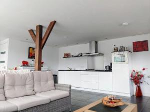 a living room with a white couch and a kitchen at Markermeerlogies in Bovenkarspel