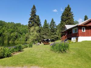 a log cabin with a large yard next to a lake at Kan-à-Mouche Pourvoirie Auberge et Chalets in Saint-Michel-des-Saints
