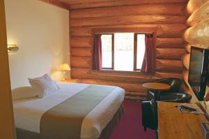 Dormitorio con cama y ventana en una cabaña de madera en Northern Rockies Lodge, en Muncho Lake
