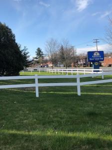 a white fence in a field with a sign at Americas Best Value Inn in East Greenbush