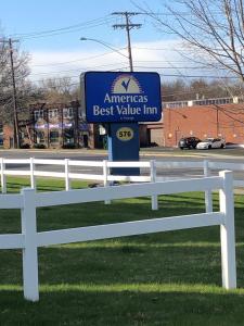 a sign for an americas best value inn next to a white fence at Americas Best Value Inn in East Greenbush