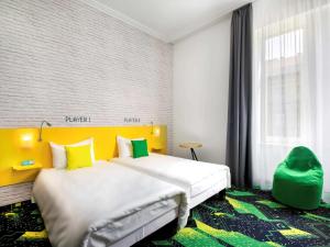 a hotel room with a bed and a yellow headboard at Ibis Styles Budapest Center in Budapest