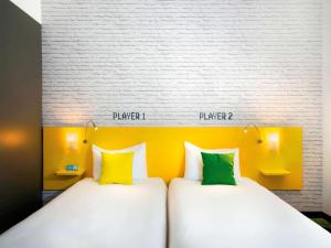two beds in a room with yellow and green pillows at Ibis Styles Budapest Center in Budapest