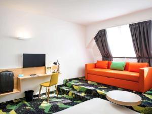 a living room with an orange couch and a desk at Ibis Styles Budapest Center in Budapest +37 photos