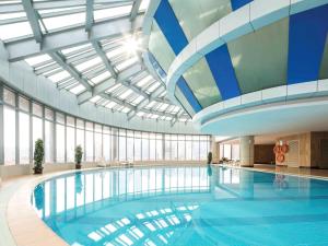 a large swimming pool in a building with a ceiling at Novotel Atlantis Shanghai - Breakfast in the clouds with river view in the revolving restaurant in Shanghai