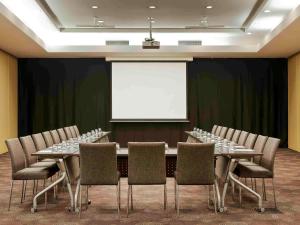 une salle de conférence avec une table, des chaises et un écran blanc dans l'établissement ibis Auckland Ellerslie, à Auckland