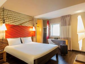 a hotel room with a large white bed and a window at Hotel ibis Lisboa Liberdade in Lisbon