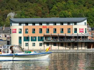 a boat in the water in front of a building at ibis Dinant Centre in Dinant