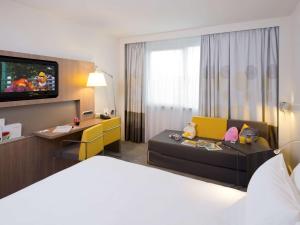 a hotel room with a bed and a tv at Novotel Leuven Centrum in Leuven