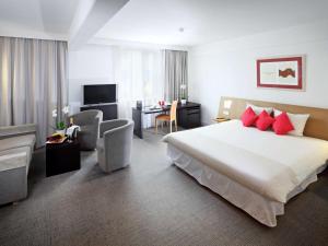 ein Hotelzimmer mit einem großen Bett mit roten Kissen in der Unterkunft Novotel Praha Wenceslas Square in Prag