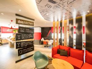 a living room with a red couch and a table at Ibis Barcelona Castelldefels in Castelldefels