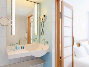 a bathroom with a sink, mirror and bathtub at Novotel München City in Munich