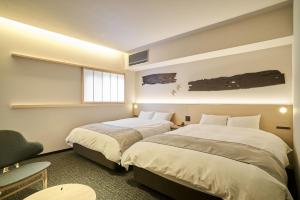 a bedroom with two beds and a chair and a window at 凜庵 LIAN_KANAZAWA in Kanazawa