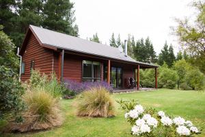 una pequeña casa de madera con jardín y flores en Woodbank Park Cottages, en Hanmer Springs