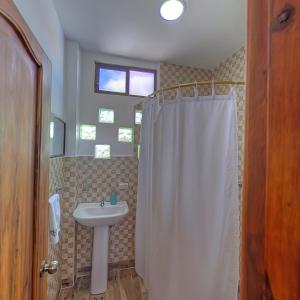 プエルトアヨラにあるガラパゴス ドリームズのバスルーム(白いシャワーカーテン、シンク付)