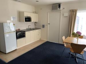 a kitchen with a white refrigerator and a table at Heyfield Motel and Apartments in Lakes Entrance