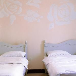 台南的住宿－花園夜市易民宿，墙上花卉画的房间里,有两张床