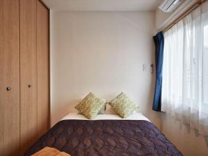 a bedroom with a bed with two pillows and a window at M´s Stay Okinawa in Chatan