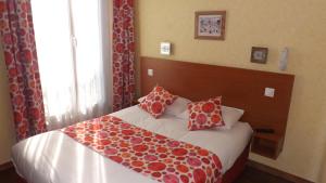 a bedroom with a bed with red and white pillows at Hôtel de la Place des Alpes in Paris