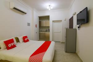 a bedroom with a bed with red pillows and a flat screen tv at Qumra Furnished Apartments in Salalah