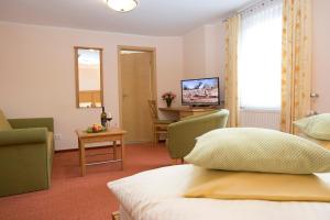 a hotel room with a bed and chairs and a television at Hotel Lindenhof in Meschede