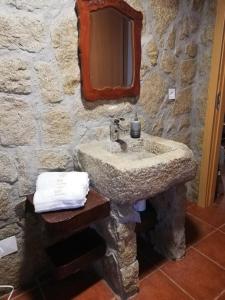 a stone bathroom with a sink and a mirror at House Diogo in Bemposta