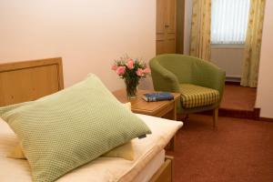 Zimmer mit einem Bett, einem Stuhl und einer Blumenvase in der Unterkunft Hotel Lindenhof in Meschede