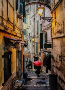 Eine Person, die mit einem roten Regenschirm durch eine Gasse geht. in der Unterkunft Casa Mirka in Sanremo