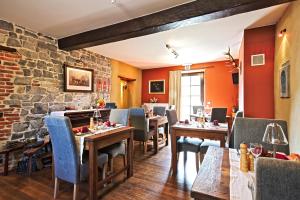 a restaurant with wooden tables and chairs and a stone wall at Hotel Le Saint Hadelin in Celles