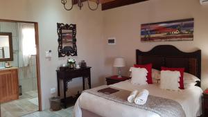 a bedroom with a large bed with red pillows at De Denne Country Guest House in Oudtshoorn