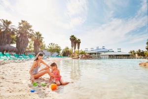 
a man sitting on a beach next to a body of water at PortAventura Hotel Caribe - Includes PortAventura Park Tickets in Salou

