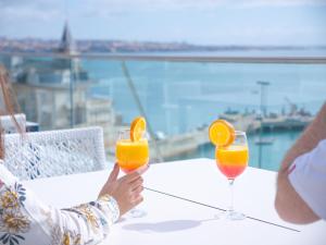 Duas pessoas sentadas numa mesa com dois copos de sumo de laranja. em Hotel Baia em Cascais