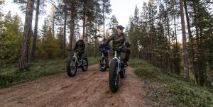 two people riding bikes on a dirt road at Aurora Village Ivalo in Ivalo
